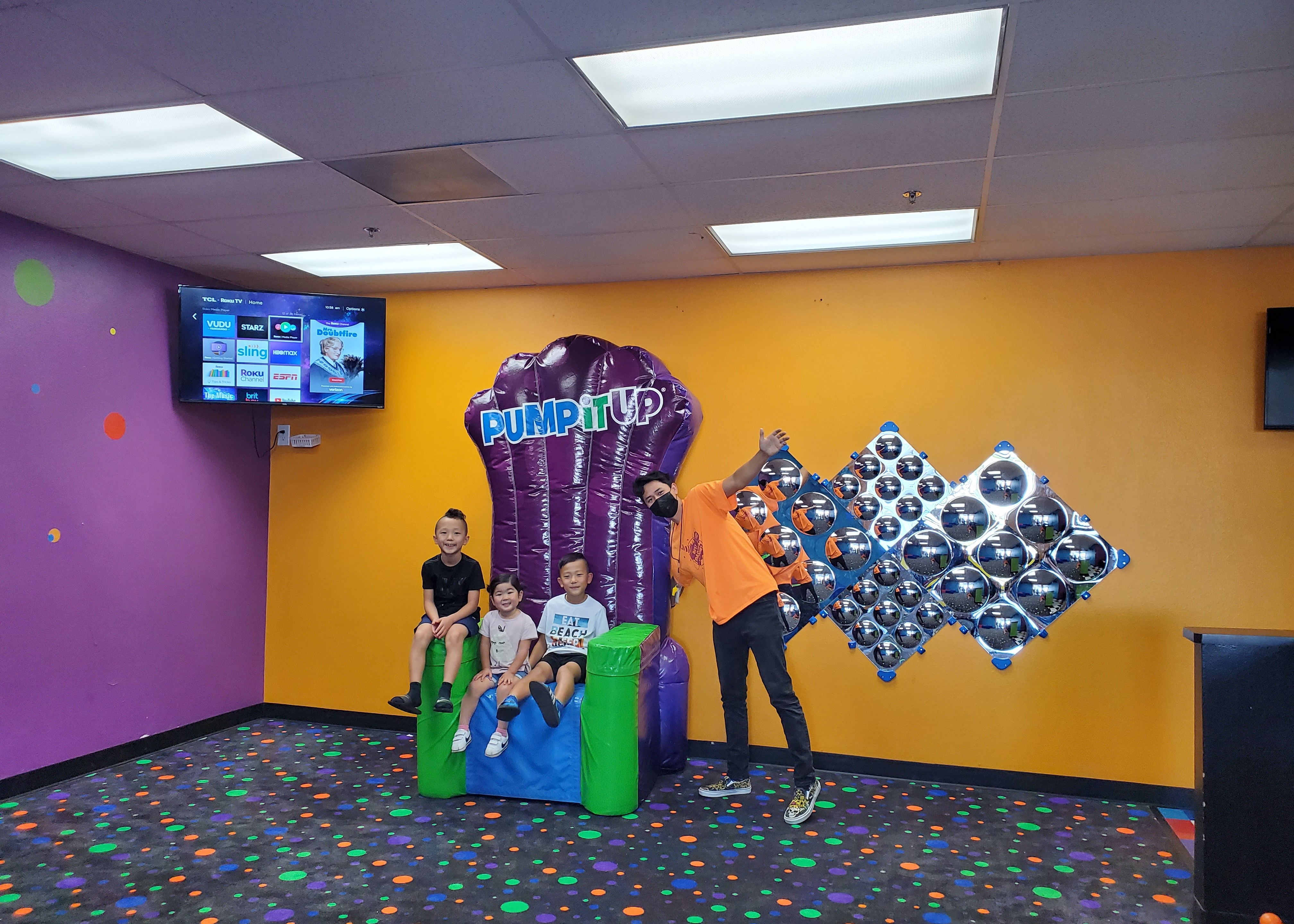 Pump It Up Lobby with kids sitting on inflatable throne and a team member standing next to them.