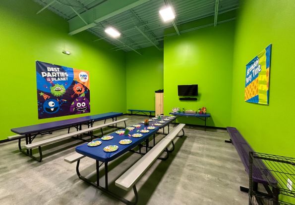 Pump It Up Overland Park Green Party room with tables and place settings for kids to eat at the 100% private birthday party.